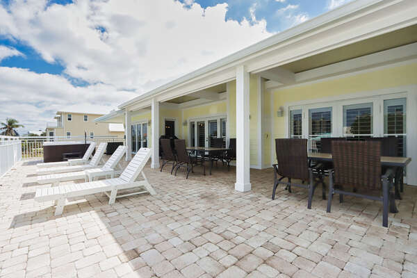 Outdoor grilling area with sun loungers, dining table, & Hot tub