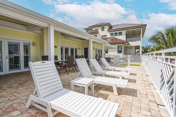 Outdoor grilling area with sun loungers, dining table, & Hot tub