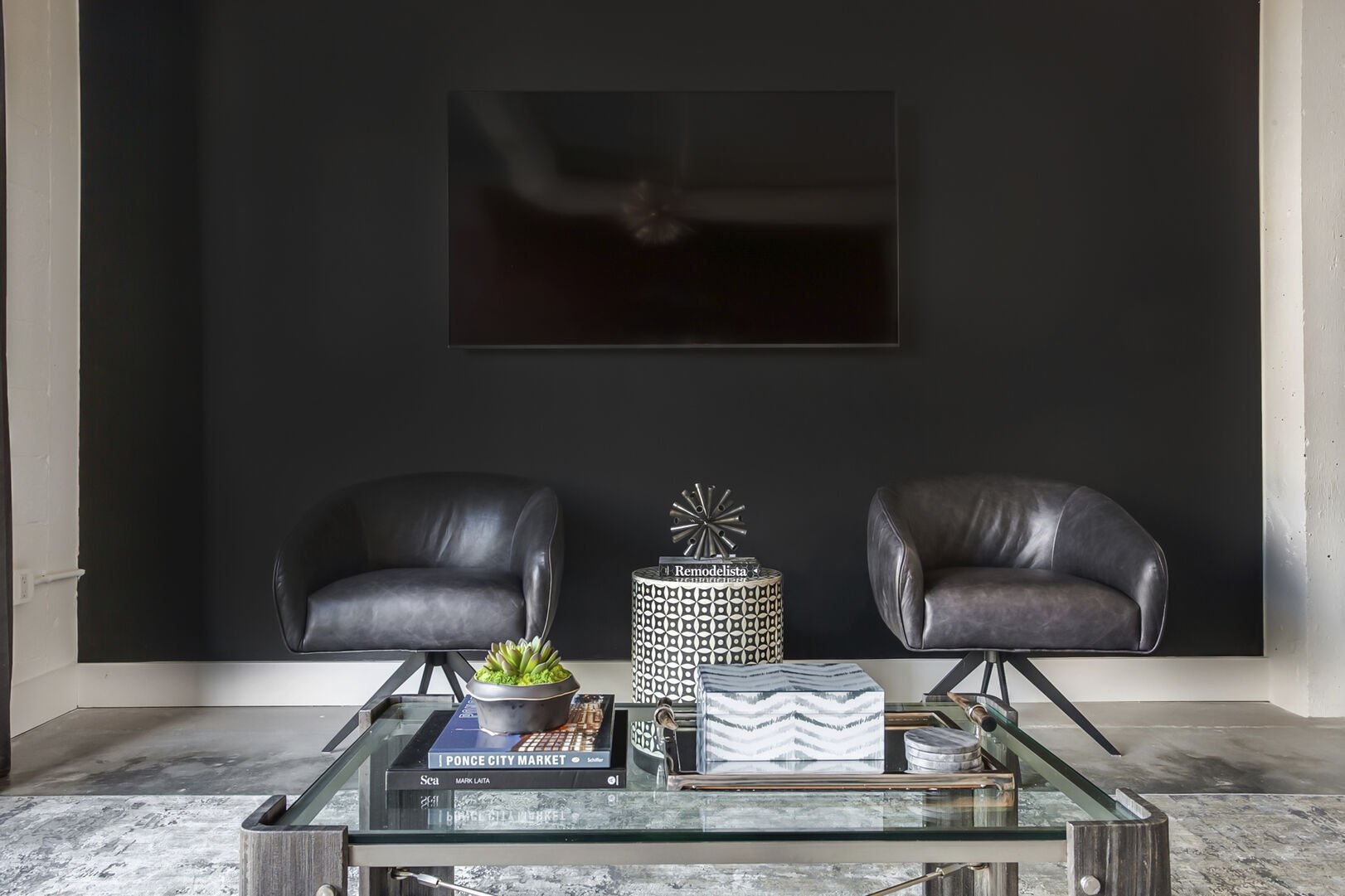 Wall-mounted TV rests above two leather armchairs in this Ponce City Market rental, and in front of a coffee table.