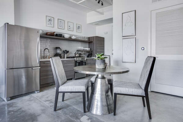 Dining area and kitchen of this Ponce City Market rental with modern appliances and a table for three.