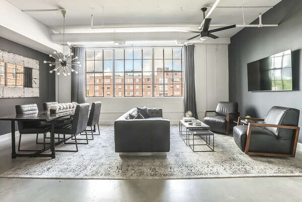 Living and dining area of this Ponce Market Apartment with ample seating and a wall-mounted TV.