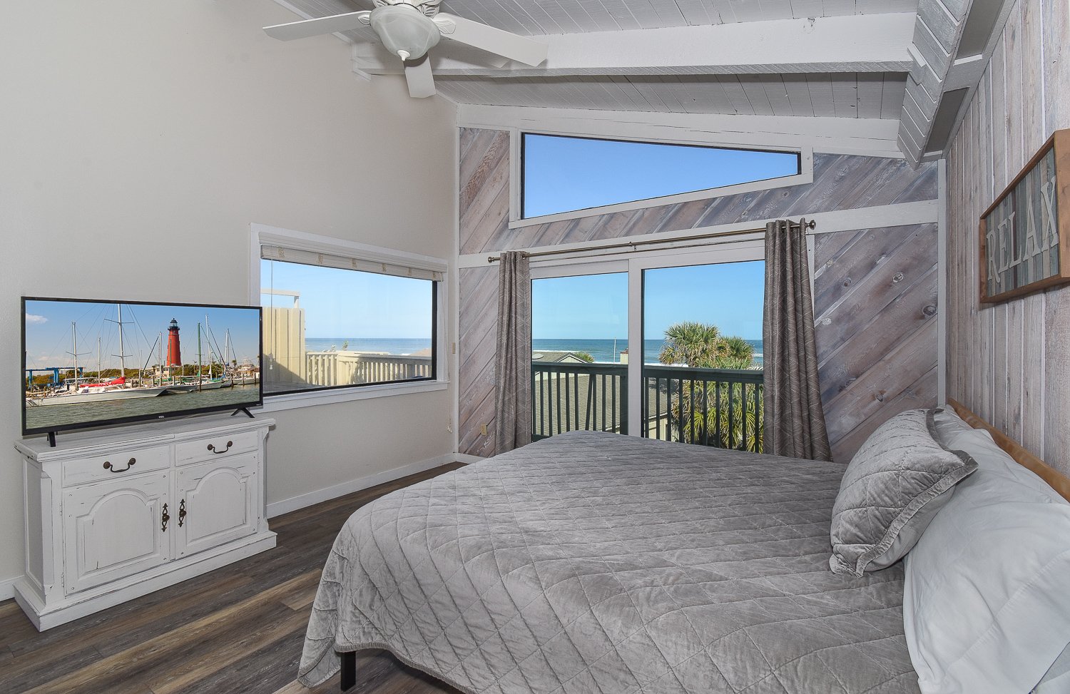 Bedroom with large bed, flat-screen tv, and multiple ocean views