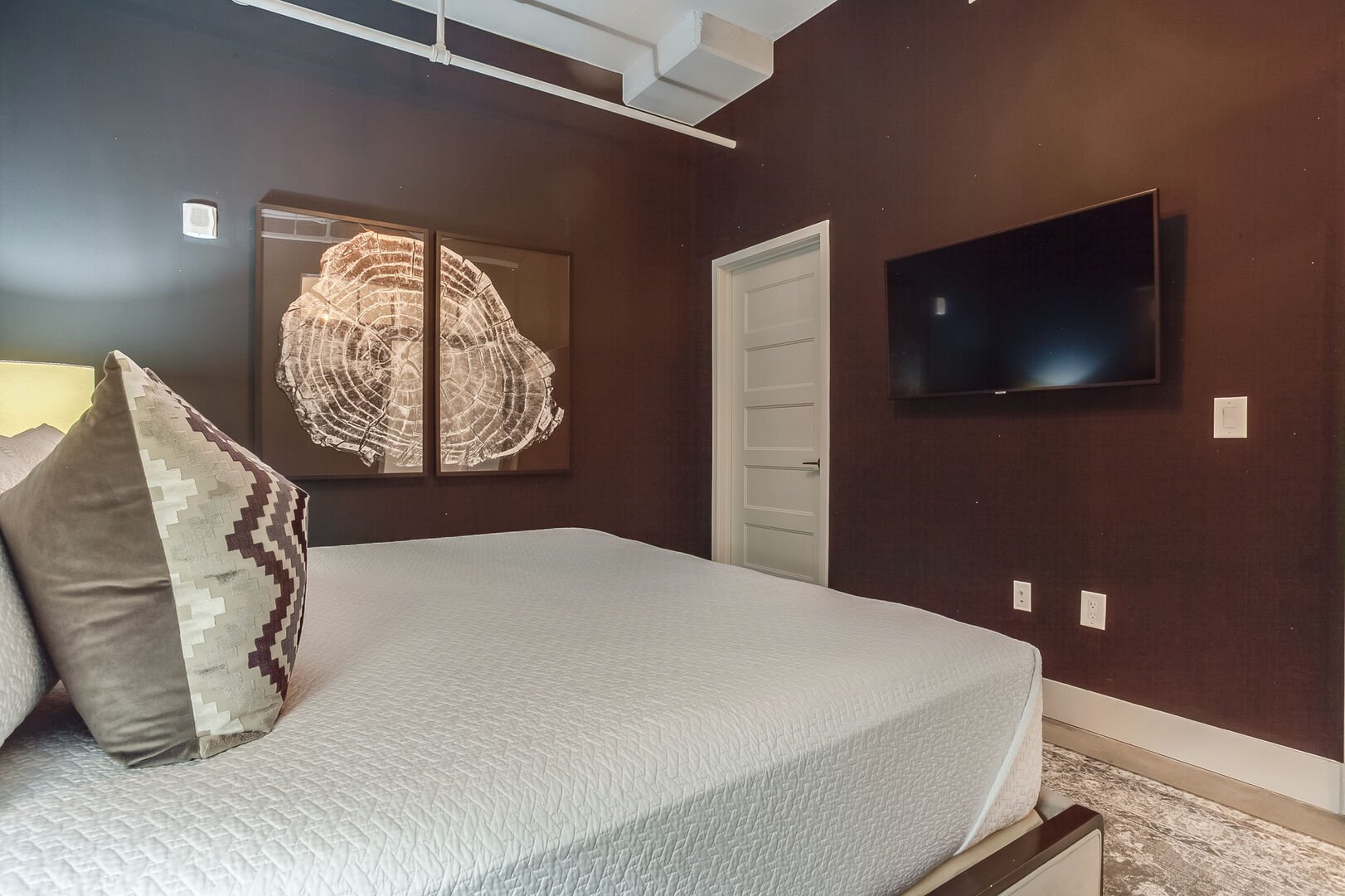 A picture of the bed and wall-mounted TV in the Master Bedroom.