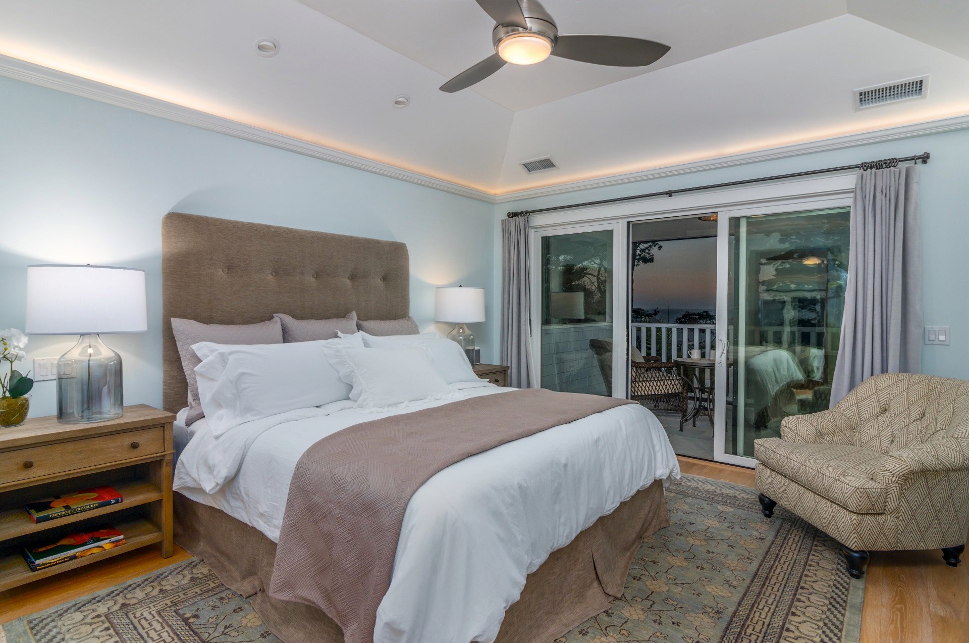 The upstairs master suite with a California King Bed, ocean views and a balcony with two chairs.