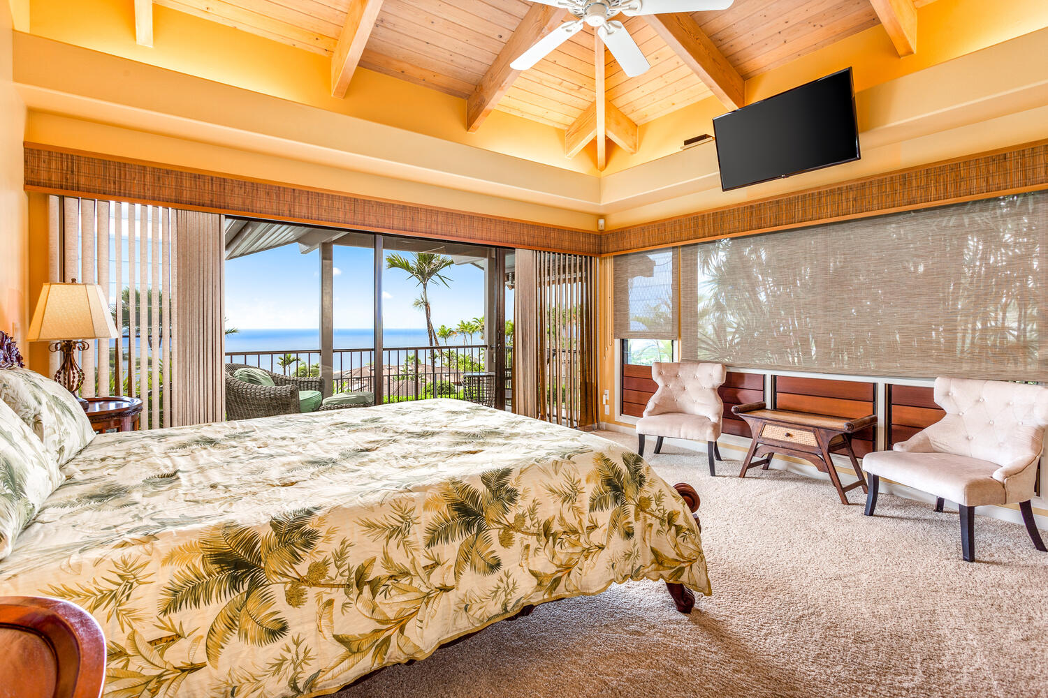 The primary bedroom has high wood ceilings and more ocean views.