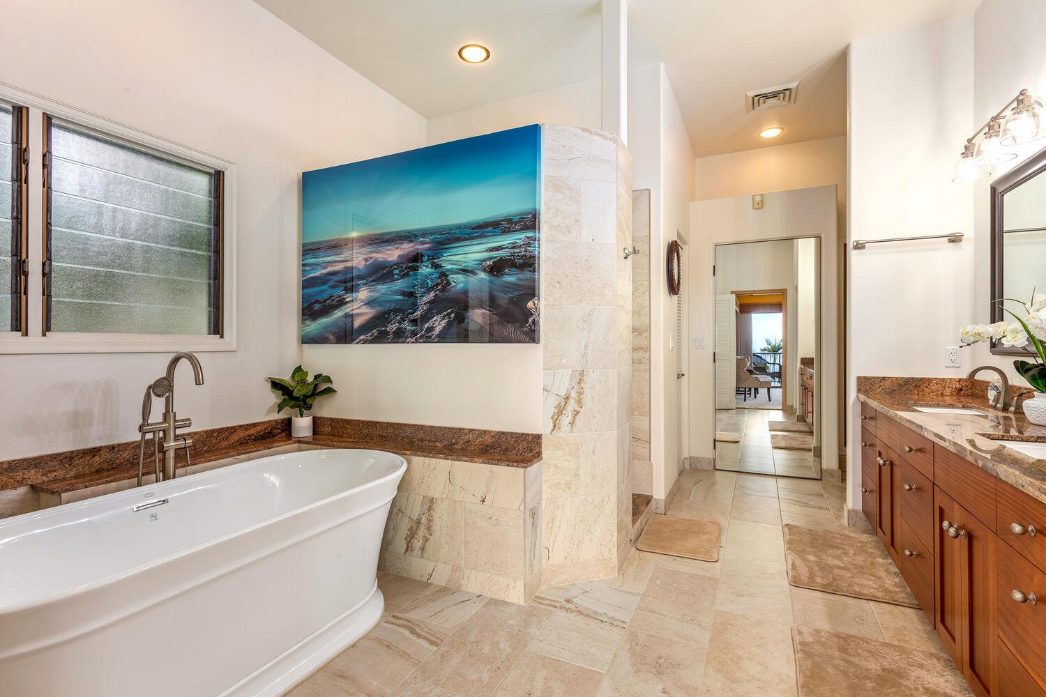 The bathroom has been remodeled to include stone counters and a beautiful architectural bathing tub.