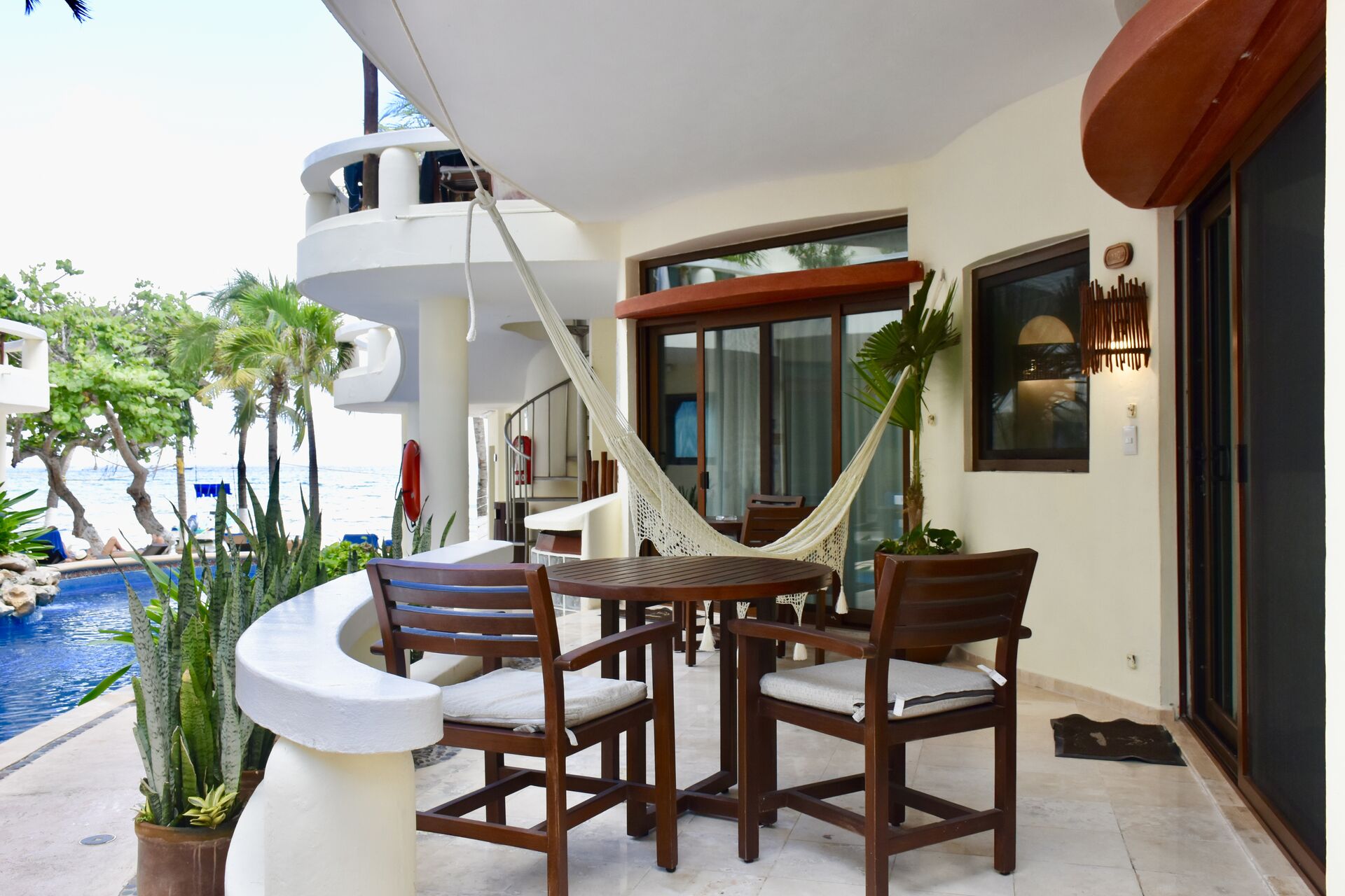 Ocean view balcony with chairs and hammock.