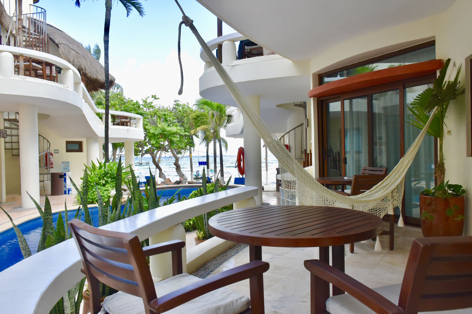 Ocean view balcony with chairs and hammock.