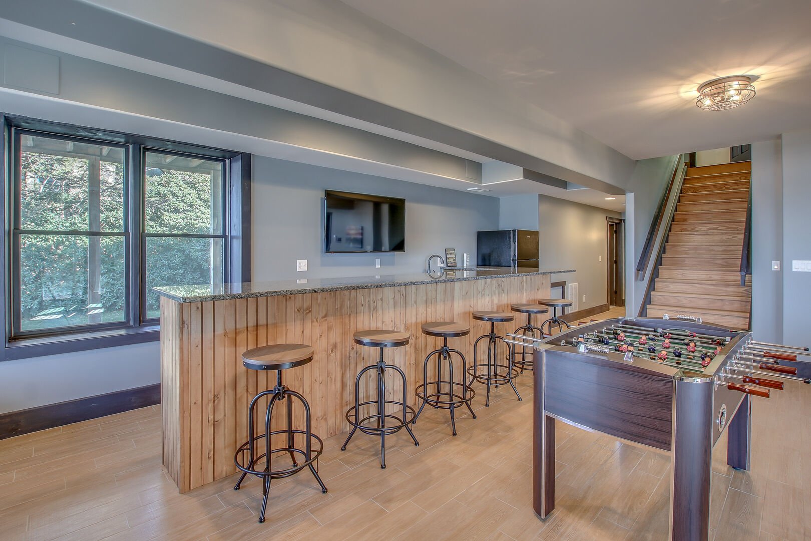 Bar seating, TV and Foosball table of game room.