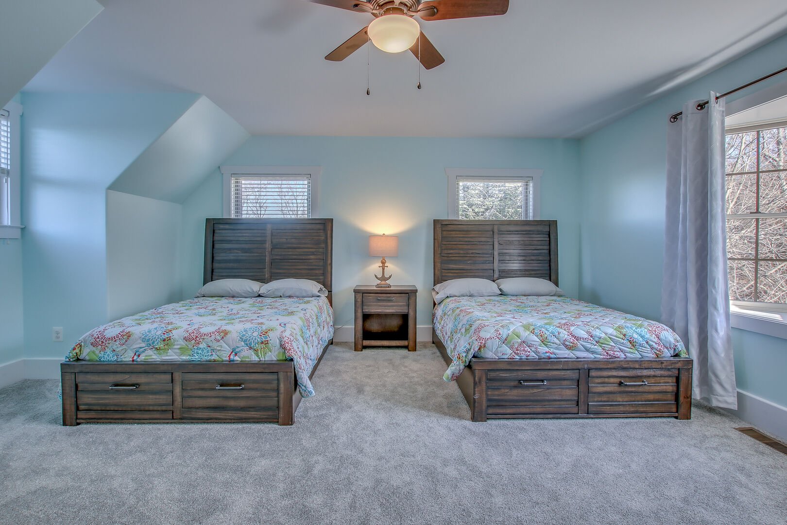 Two side-by-side beds with high headboards, with a nightstand and lamp between them.