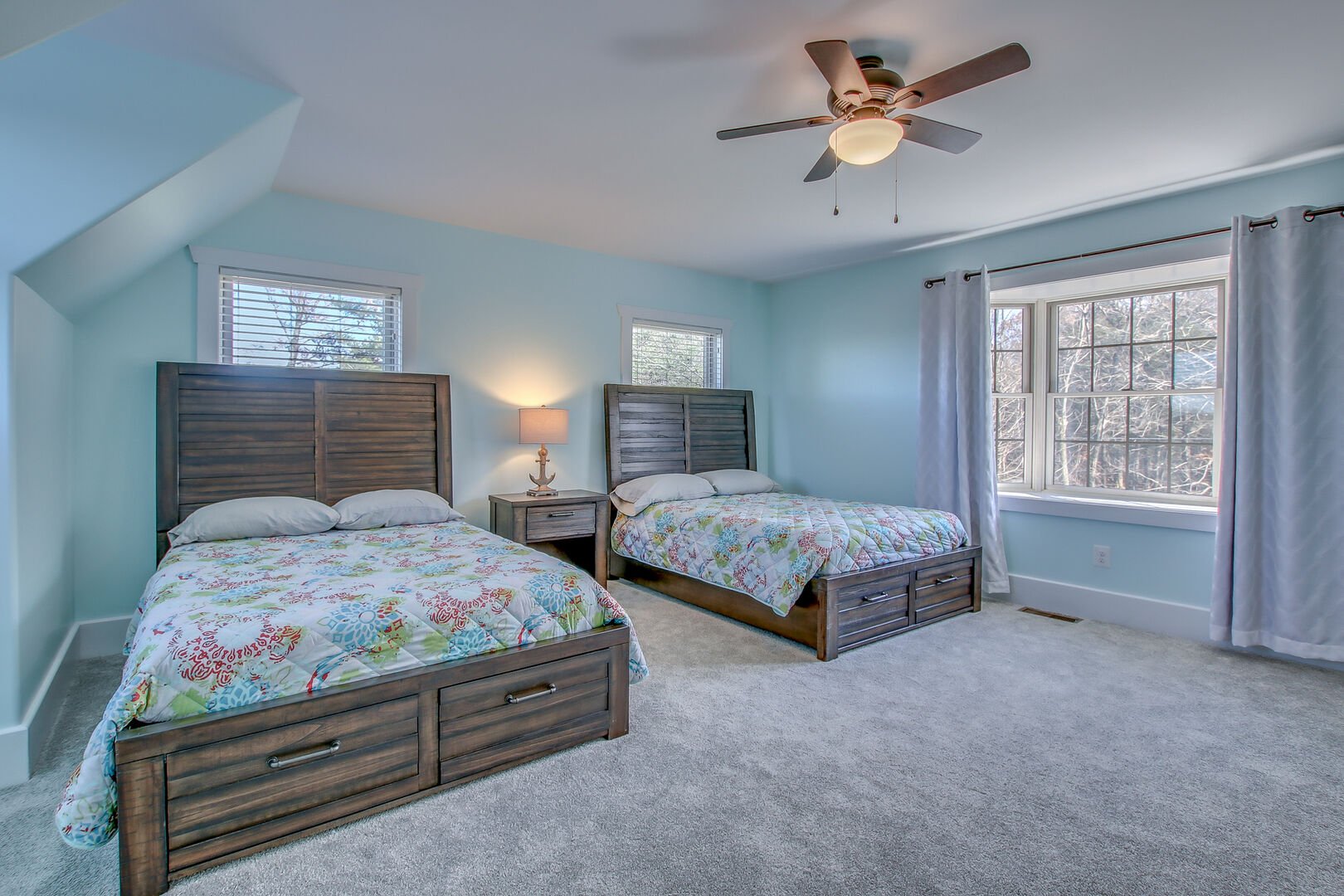 Two beds side by side in one of the bedrooms of this Poconos rental  by the lake, with a nightstand in between.