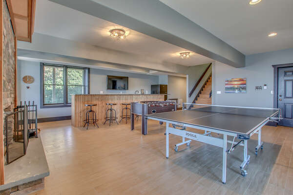 Ping pong table, Foosball table, and bar seating facing a TV of the game room on the lower floor.