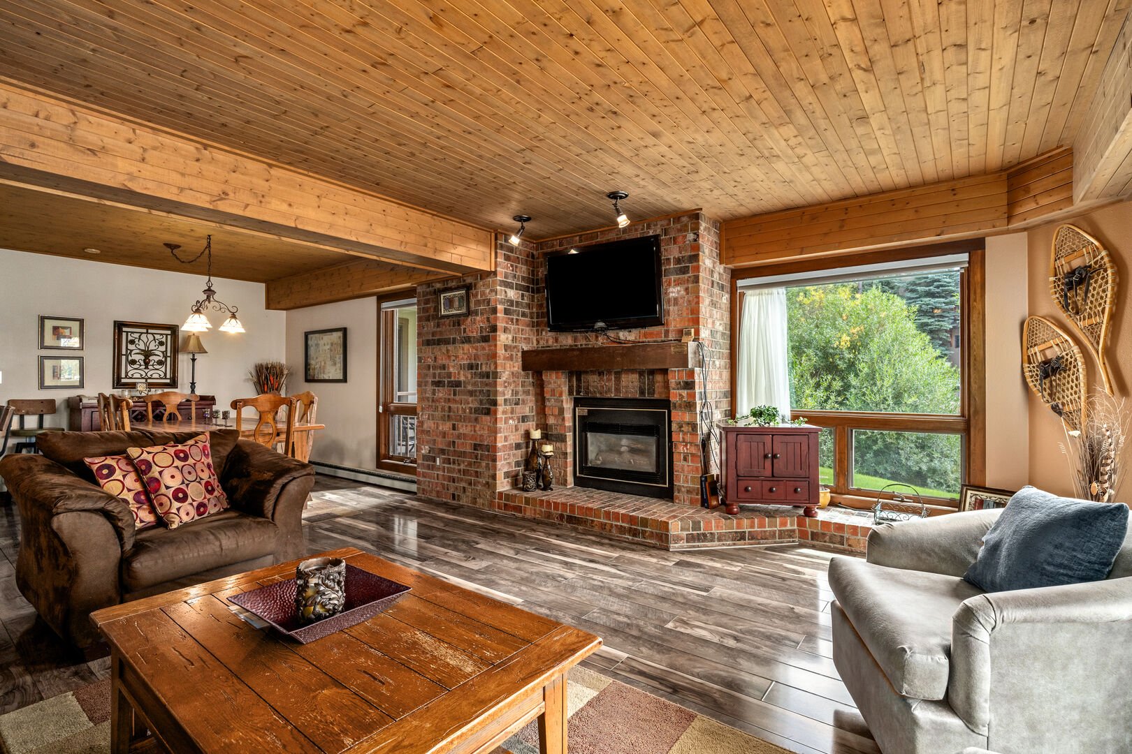 The living area incorporates exposed brick and natural wood, with a large TV, gas fireplace and the entrance to the deck.