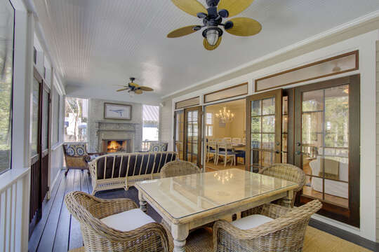 A wider angled photo of the sun room, with dining table, living area, and fireplace.