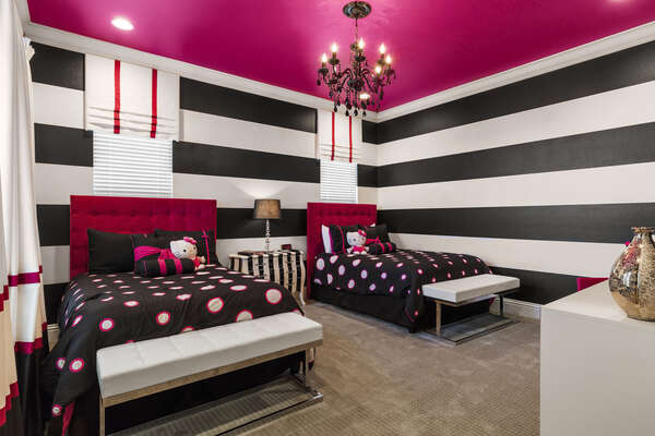 Kids will love this glamorous bedroom with pink and black accents, a chandelier and two full beds