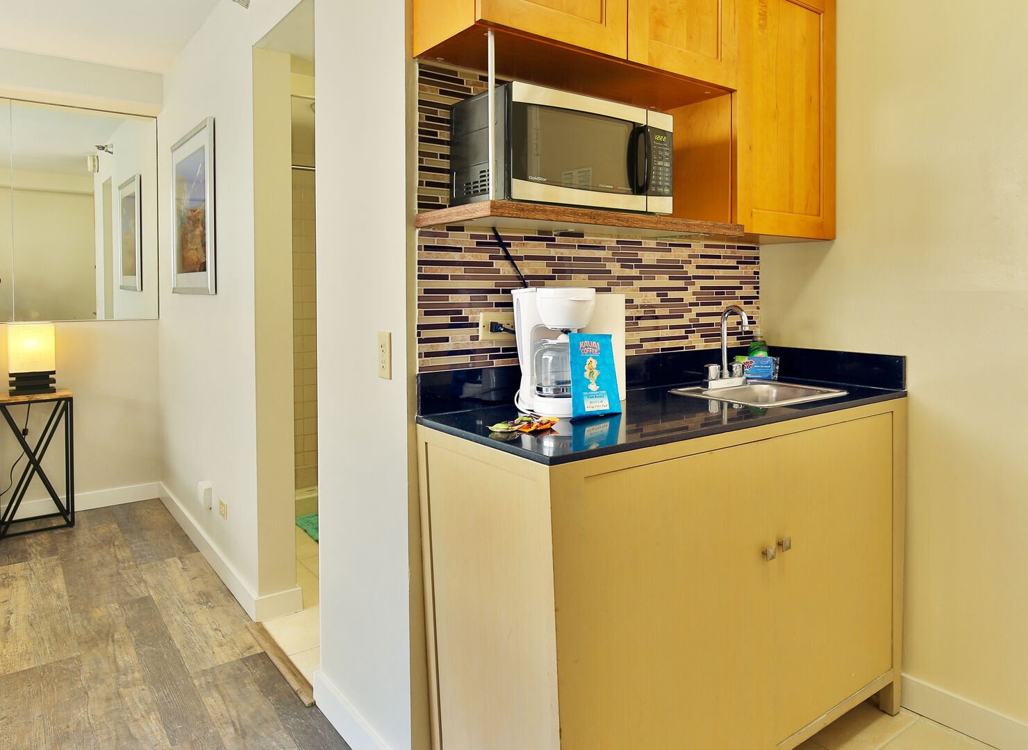 The kitchenette is equipped with a microwave, a mini refrigerator, a toaster, a coffee maker, dishes, silverware, and basic cooking utensils.