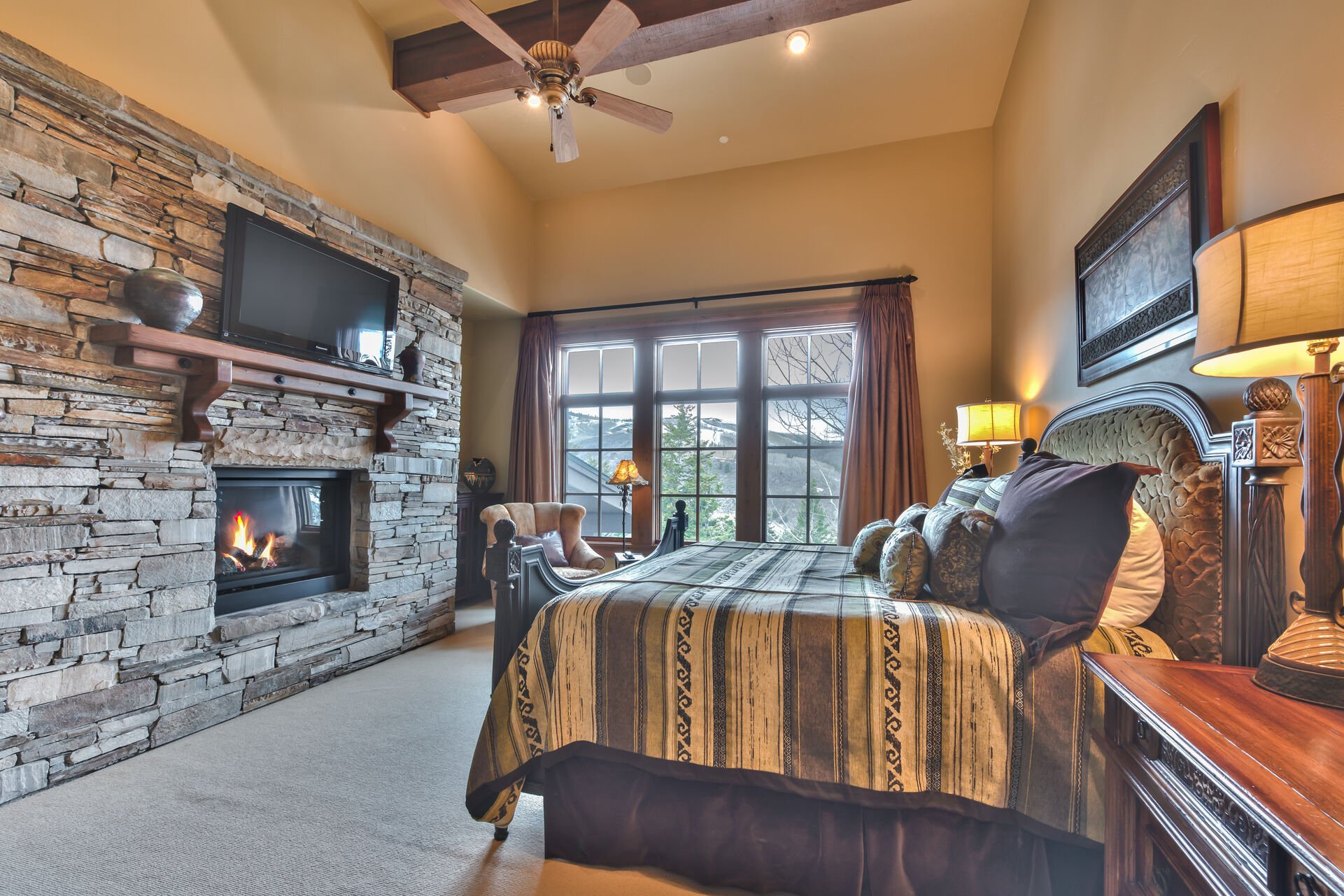 Grand Master Bedroom with a King Bed, Gas Stone Fireplace, 40'' HDTV, and Mountain Views