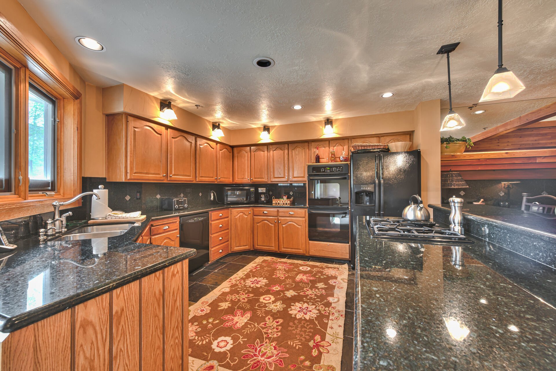 Fully Equipped Kitchen with a 4-Burner Gas Stove, Double Ovens, Granite Counter Tops, and Stone Tile Flooring
