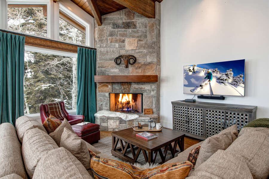 A wall-mounted TV, woven metal buffet, and beamed ceiling add heft to this high mountain retreat.