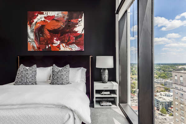 Master Bedroom Includes a Black Wall, Velvet Bedframe, and Art.