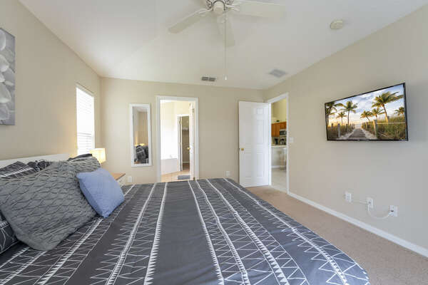 Master suite showing king bed and TV. You see bathroom and living room access doors in the photo