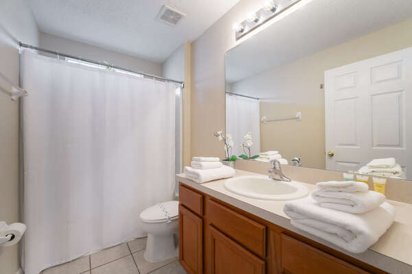 Shared bath showing shower/tub combo, single sink vanity, toilet.
