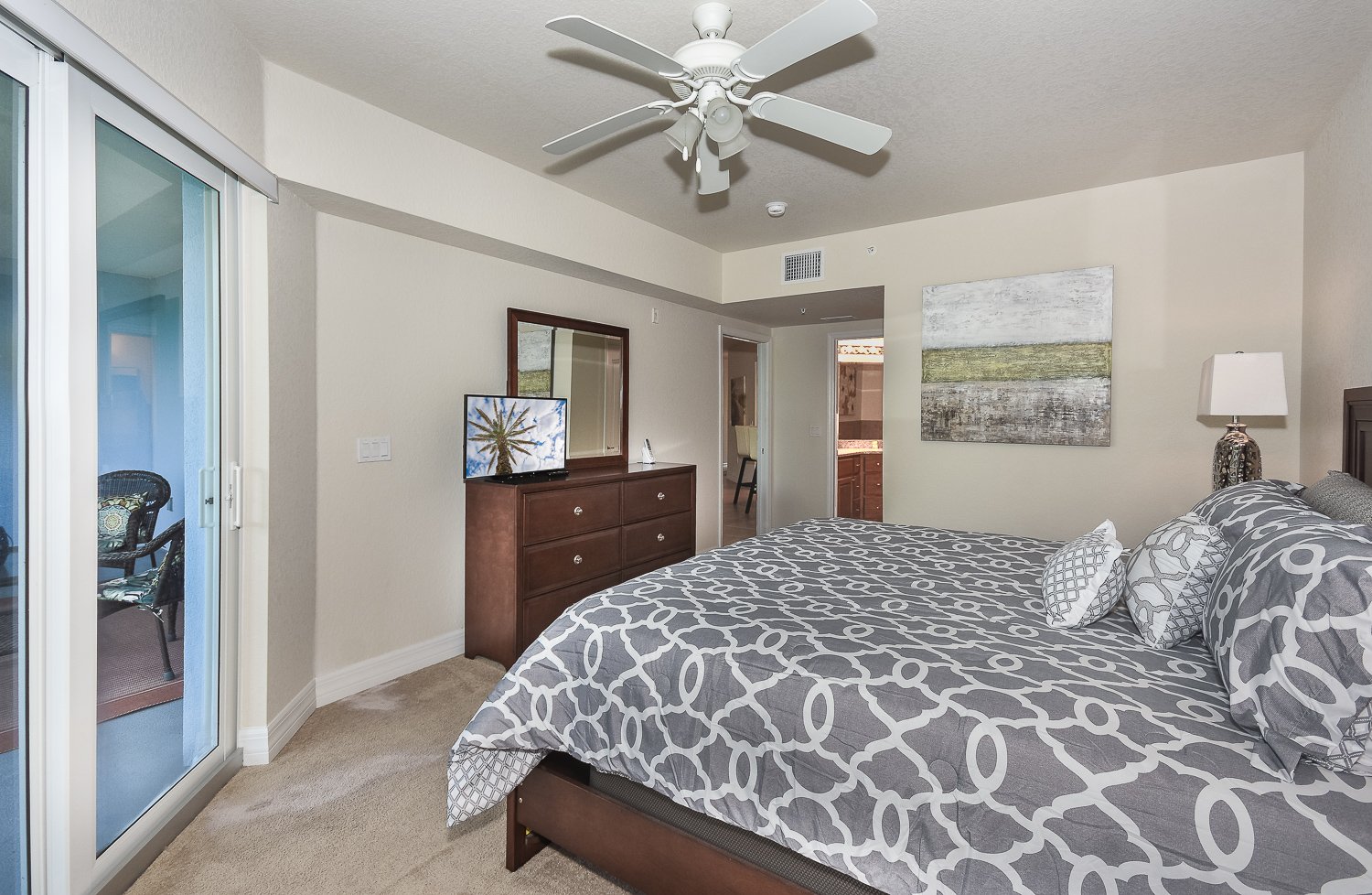 Large bed, ceiling fan, smart TV, dresser, and mirror