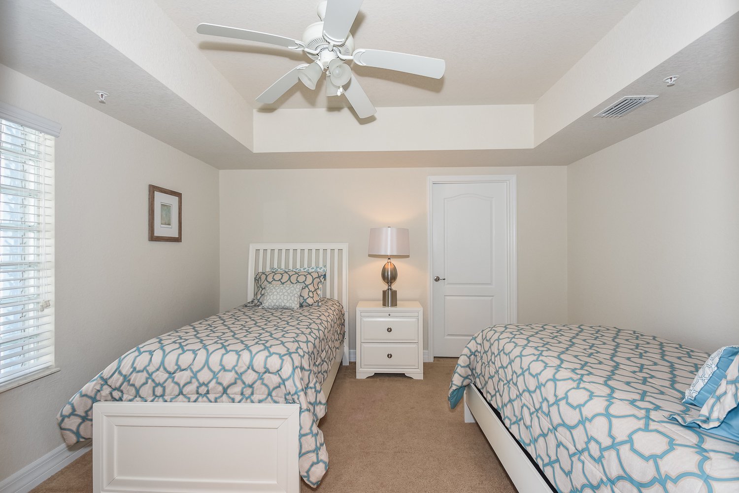 Bedroom with two twin size beds, nightstand, lamp, and ceiling fan