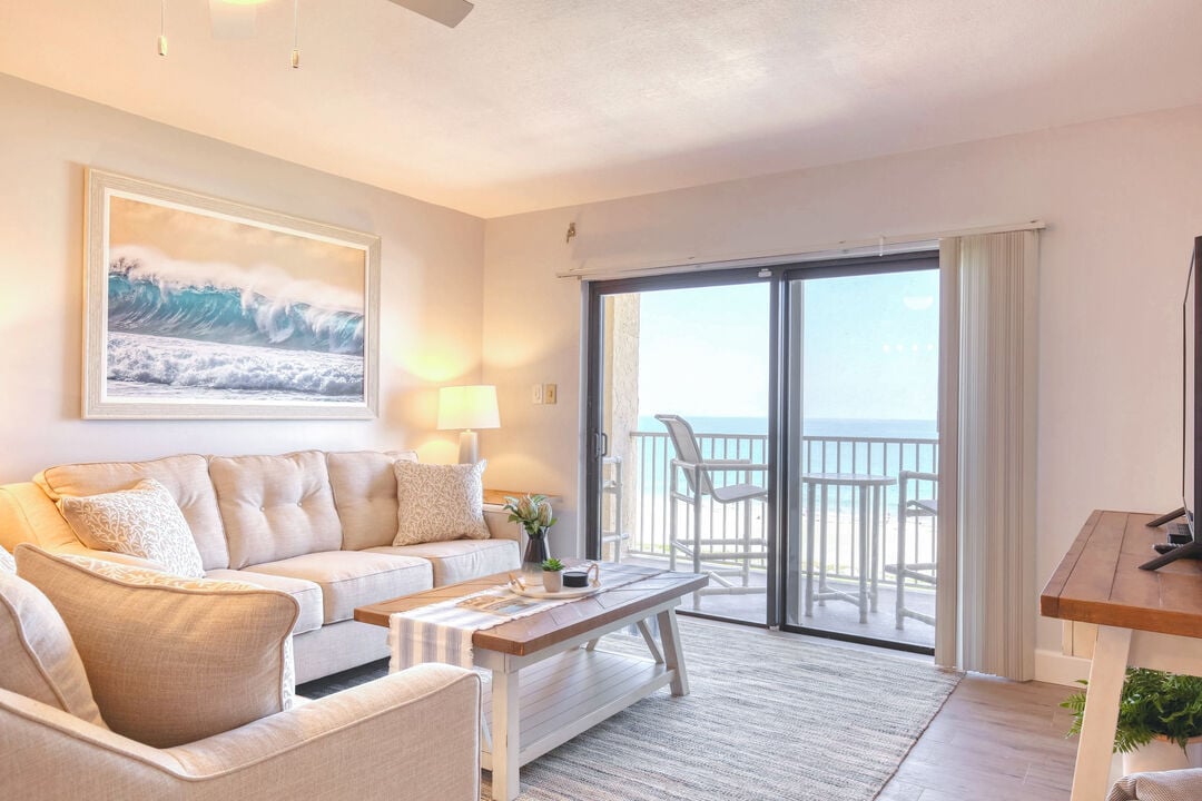 Cozy living room with a beachside balcony, soft lighting, and coastal decor.