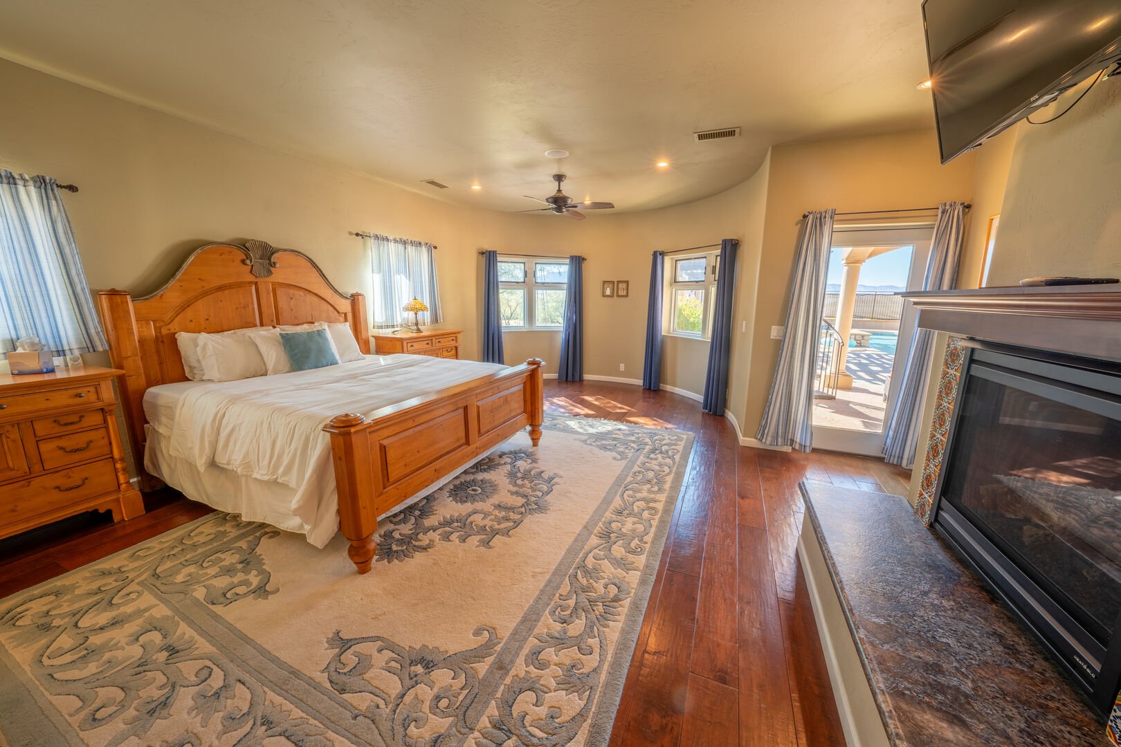Master Bedroom With Fireplace, TV, And Access To Pool Area