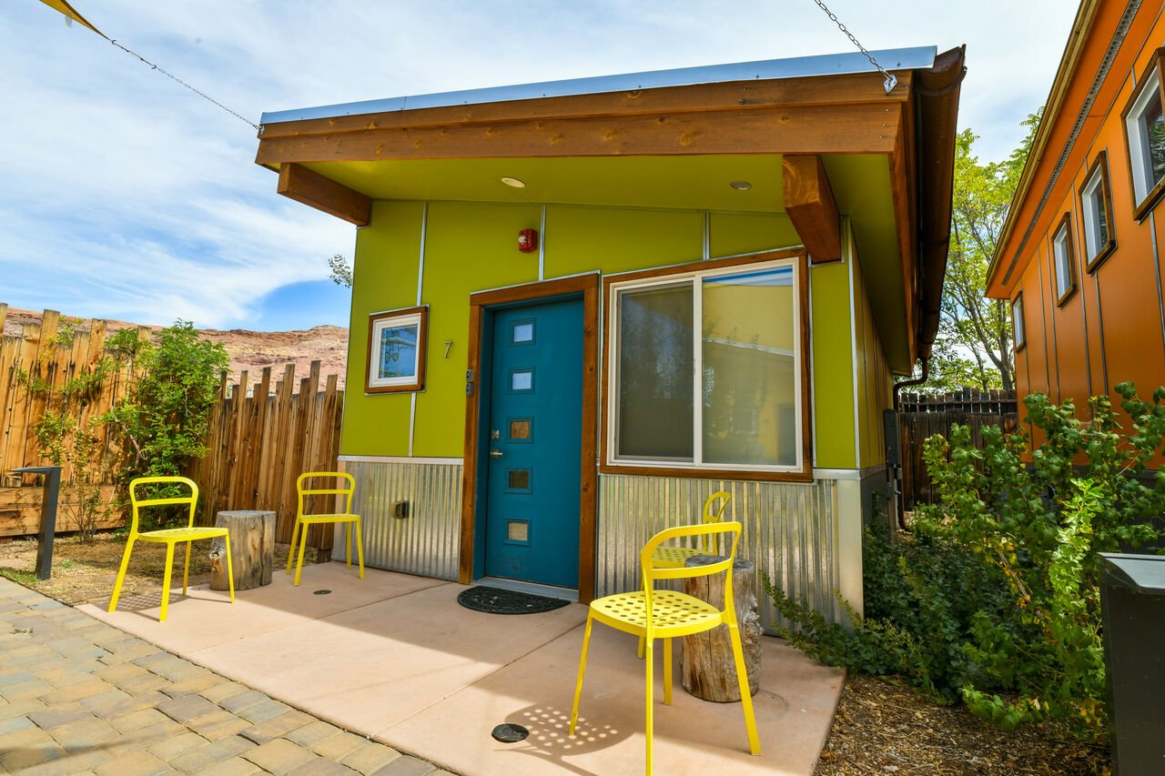 Exterior of this Moab vacation rental, with its yellow patio chairs and unique green paint job.