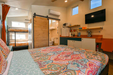 Studio View from the head of the bed, displaying the kitchenette and side room with bunk beds.