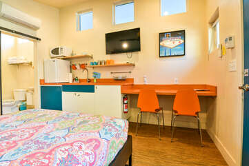 Kitchenette with an orange color scheme, wall-mounted TV.