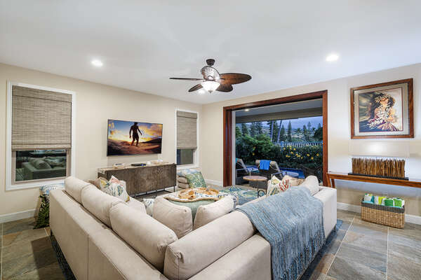 Photo taken from behind the sectional couch, displaying wall-mounted TV and door to back lanai.