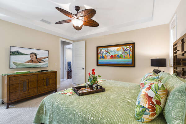 Master bedroom with a flat-screen TV, large bed, and ornate ceiling fan.