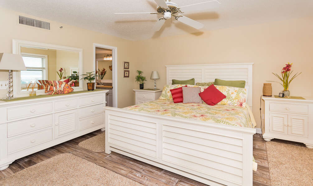 Large bed, ceiling fan, nightstands, dresser, and mirror