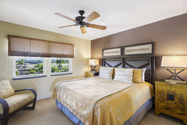 Bedroom 2 of this Kona Hawai'i vacation rental with a large bed, armchair, and nightstands.
