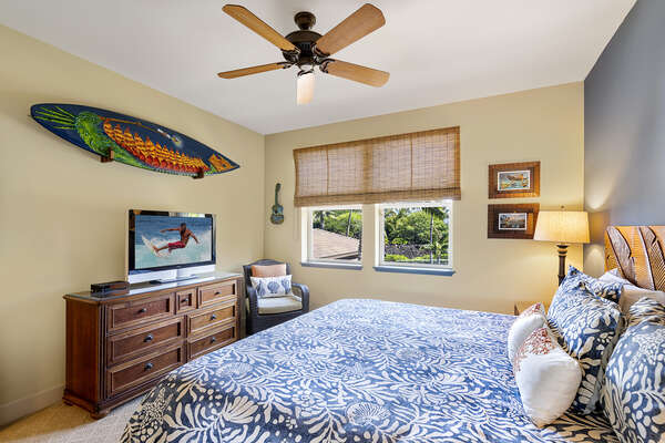 A surfboard hangs over a flat-screen TV in the 3rd bedroom, in front of a large bed.