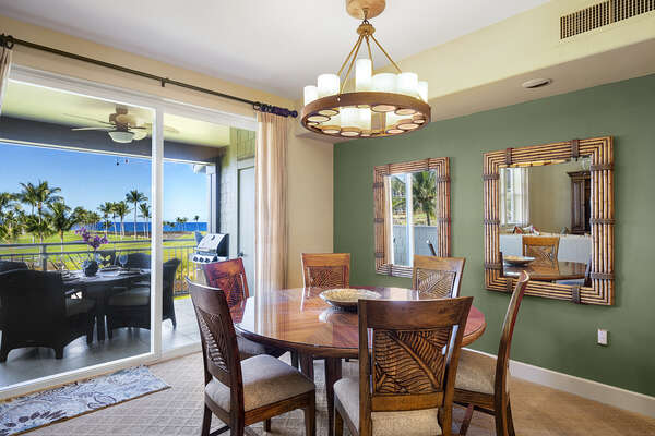 Dining area with seating for 6 and ample lighting from the chandelier and sliding glass door to the outside.