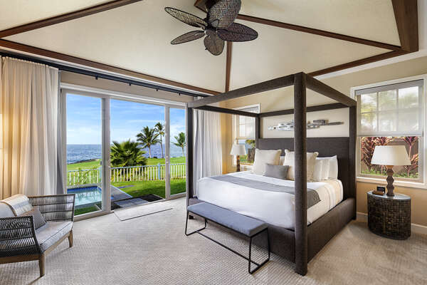 Primary bedroom of the Holua Kai Kona condo rental with ornate bed frame and armchair.