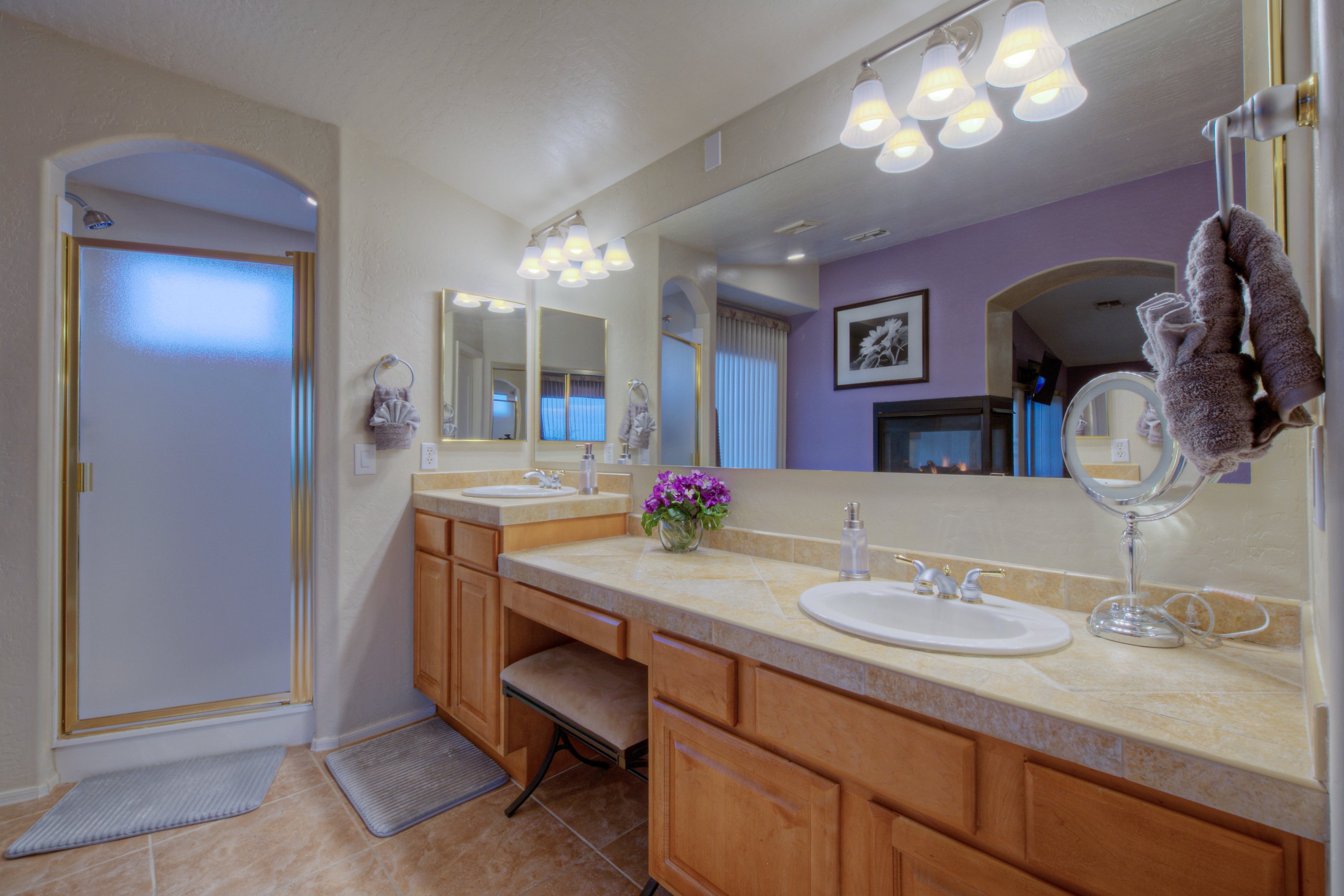 Primary suite includes a walk-in shower, dual vanity sinks and seated area for cosmetics and hair.