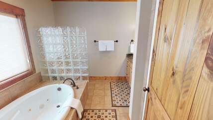 Located within the master bedroom is the ensuite bathroom with a standing shower, soaking tub, toilet, and mirror vanity.