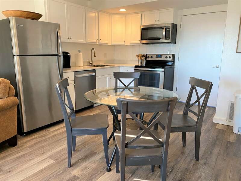 Dining table, chairs, and the kitchen with stainless steel appliances