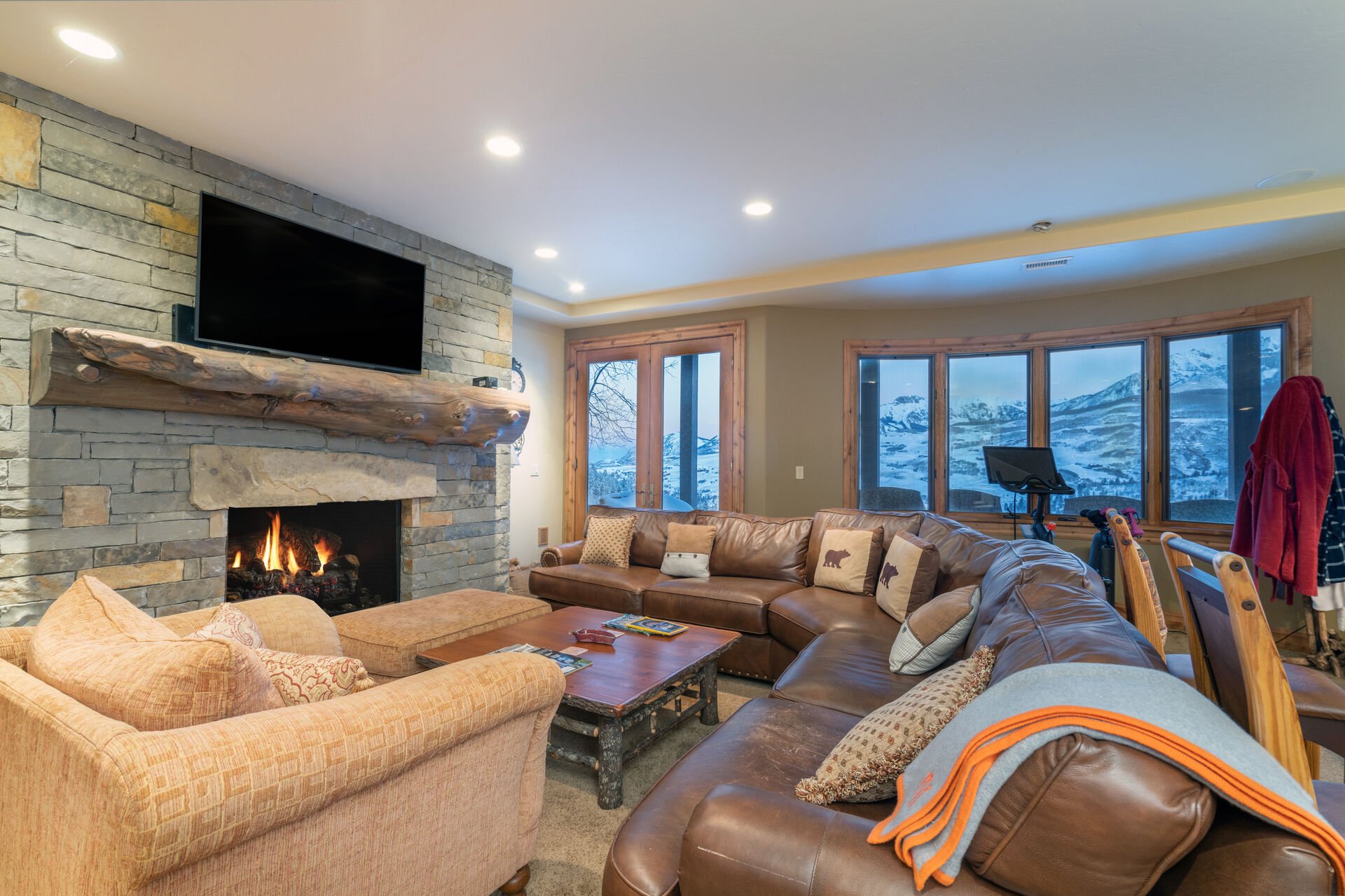 The living area of this Telluride golf rental is complete with a long sectional couch, armchair, fireplace, and TV.