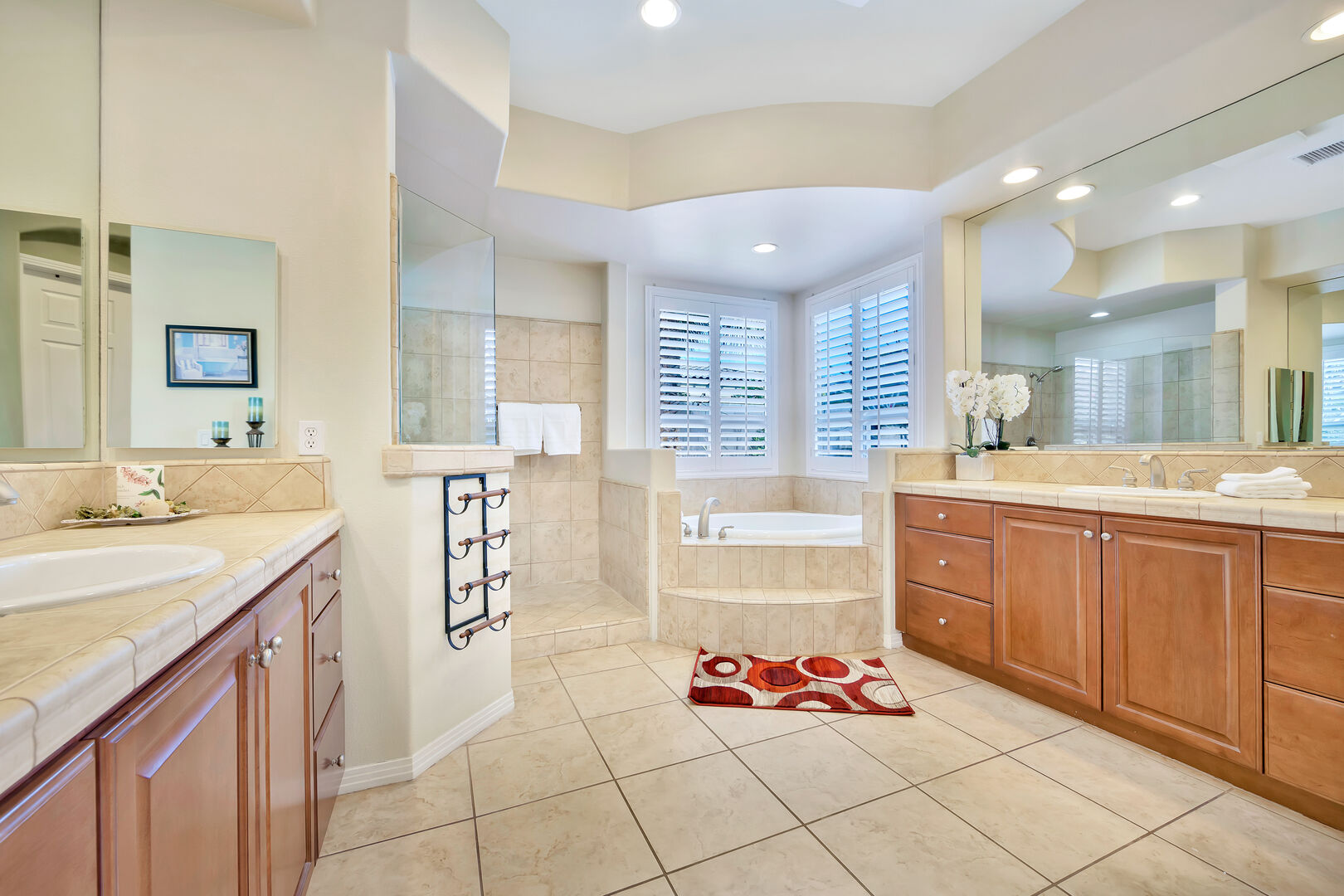 Master Suite 1 private, en suite bathroom features a soaking tub, tile shower and two vanity sinks.