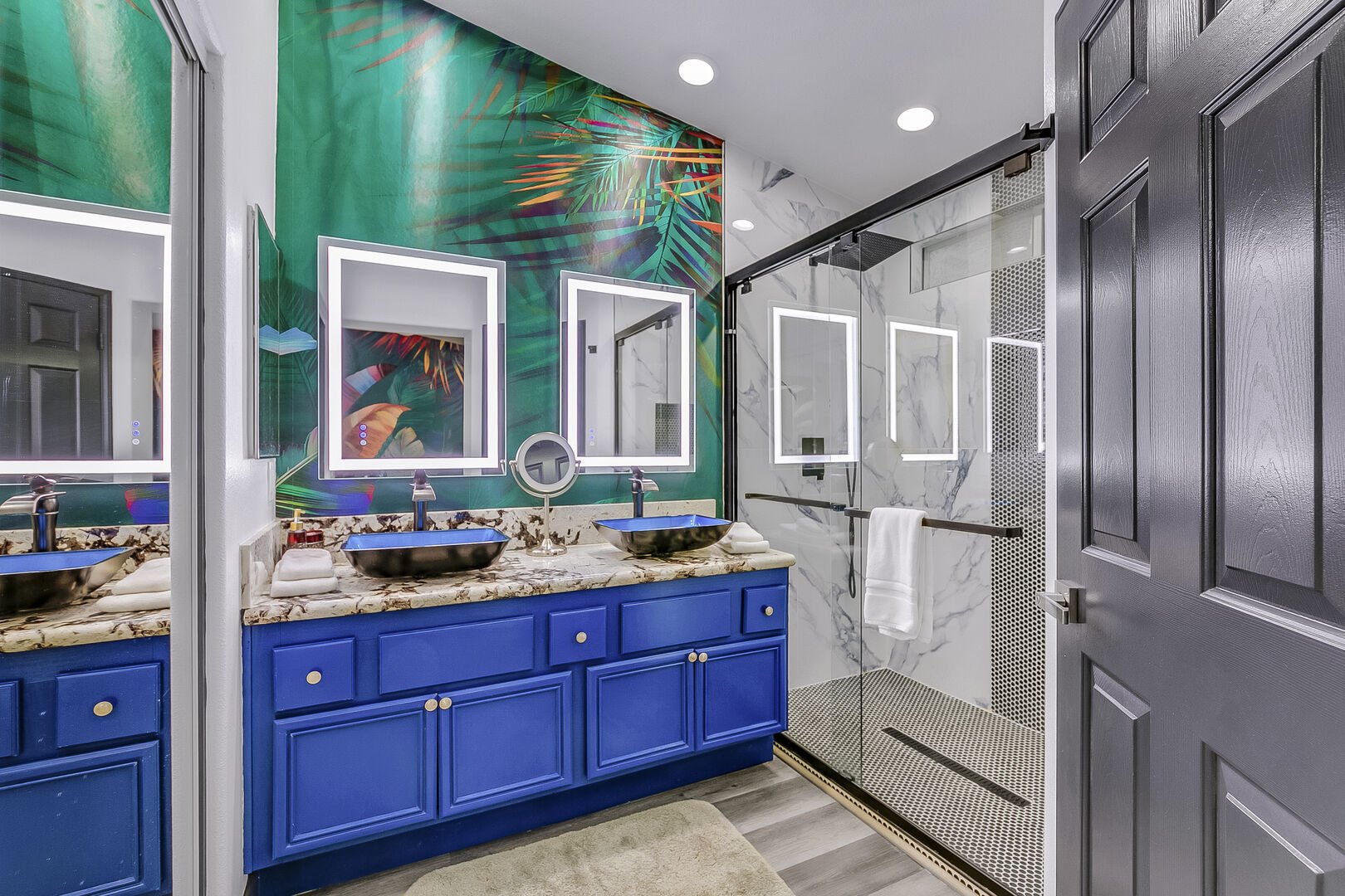 The en suite bathroom is a private oasis, complete with a tiled shower, marble countertops, dual vanity sinks, and a spacious walk-in closet equipped with shelving.