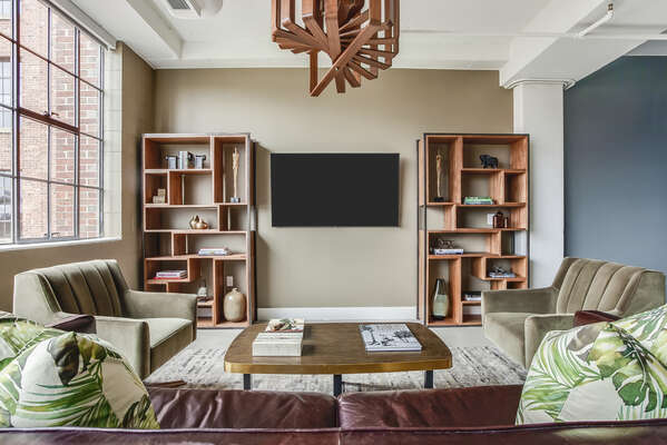 Living Area with Leather Sofa, two Chairs, TV, and Bookshelves