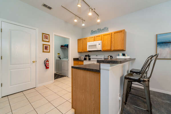 Kitchen showing access to laundry room with breakfast stools