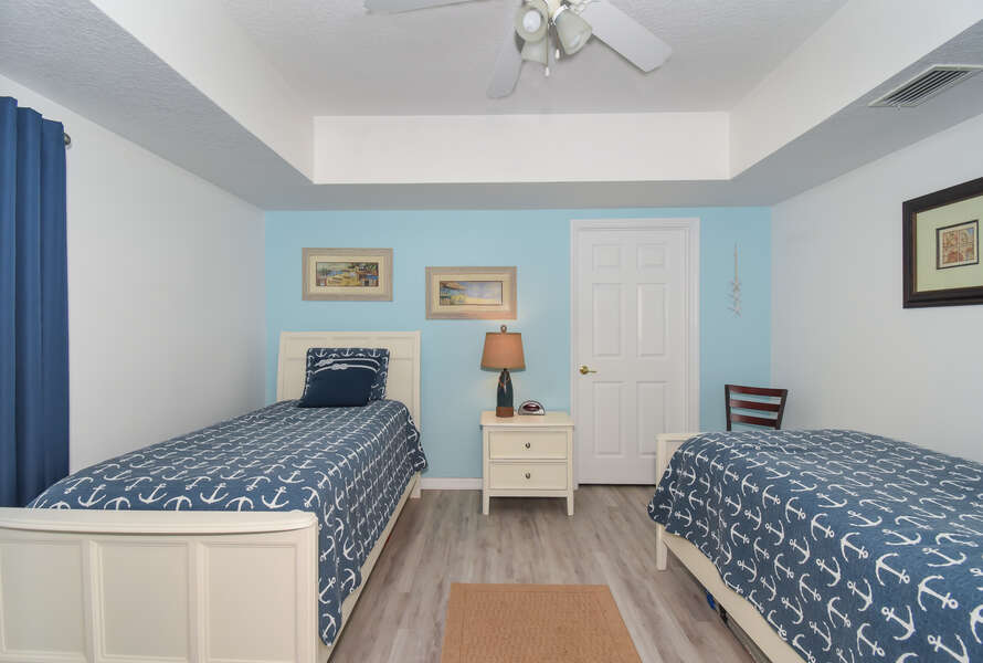 Bedroom with two beds, nightstand, table lamp, and ceiling fan
