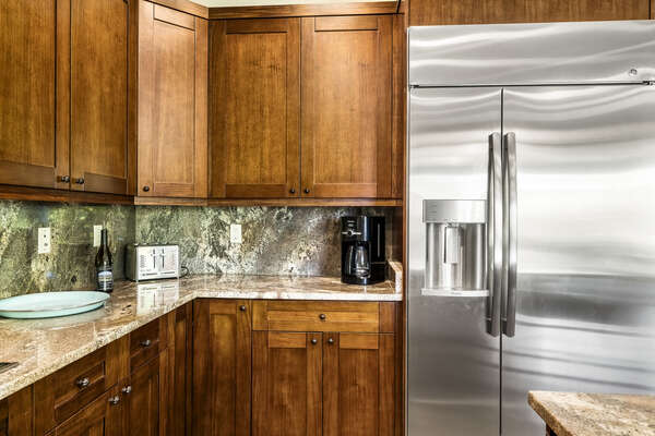 The large stainless steel fridge of the kitchen, next to the coffee maker.